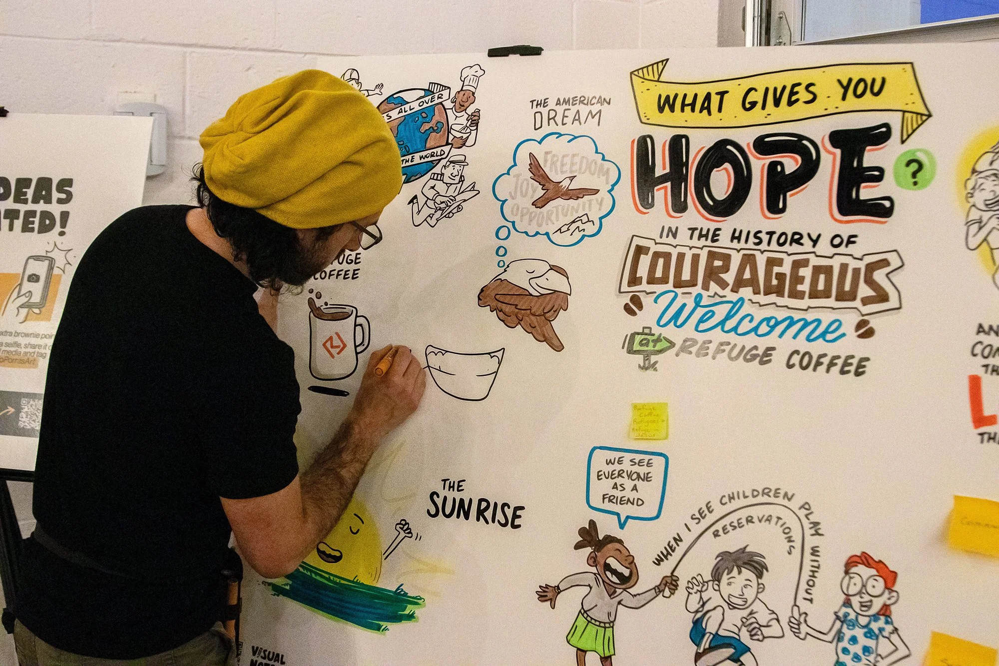 Alejo Porras drawing live an interactive board at the anniversary celebration of Refuge coffee in Clarkston, Georgia