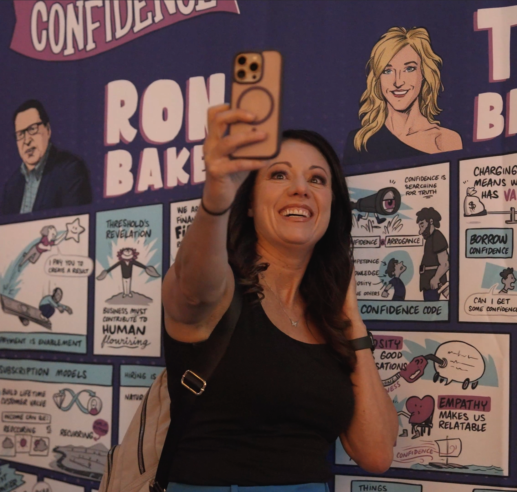 Conference attendee taking a selfie with the banner containing the visual notes created by Alejo Porras.