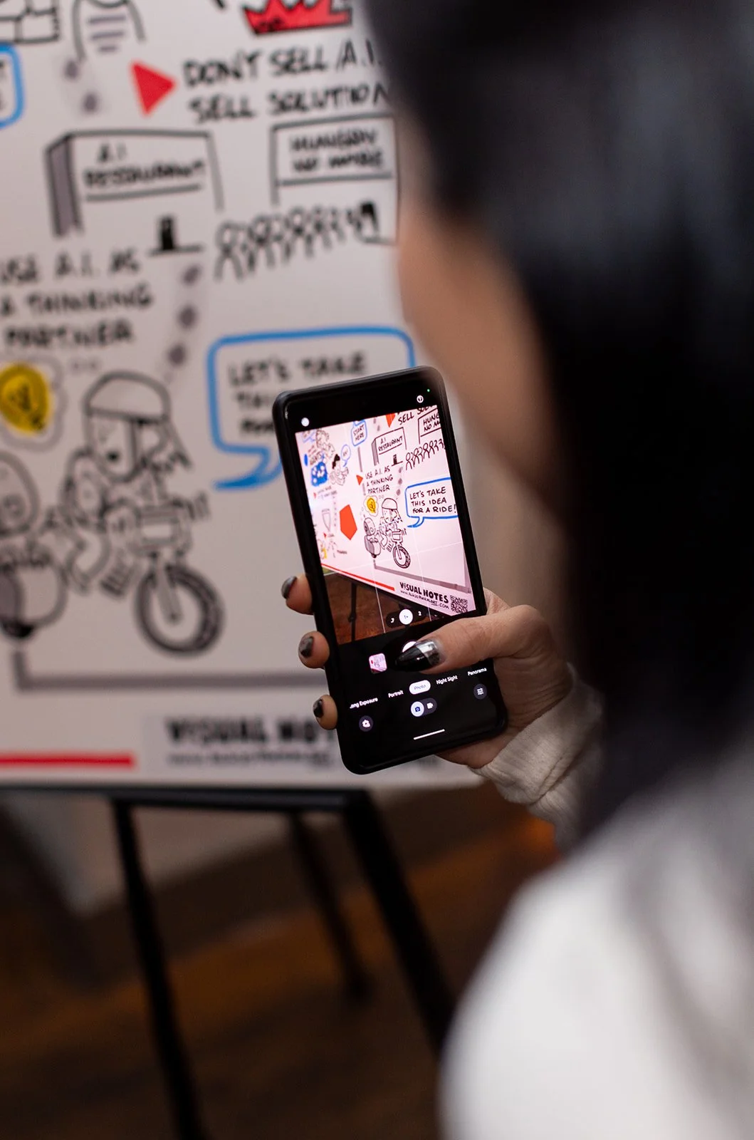 Person takes photo with her phone on the interactive visual mural Alejo created.