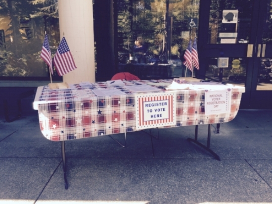 Table decorated with flags, stickers, pens, and forms for National Voter Registration Day. Photo courtesy of Valerie Walston.