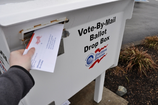 A voter inserts a ballot into one of Pierce County's drop off boxes. Photo by Whitney Rhodes.