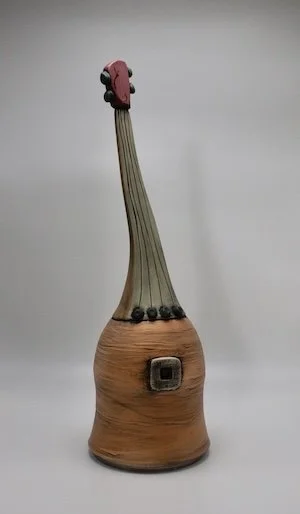 Clay sculpture of a guitar with a rounded base, long neck, and tuning pegs.