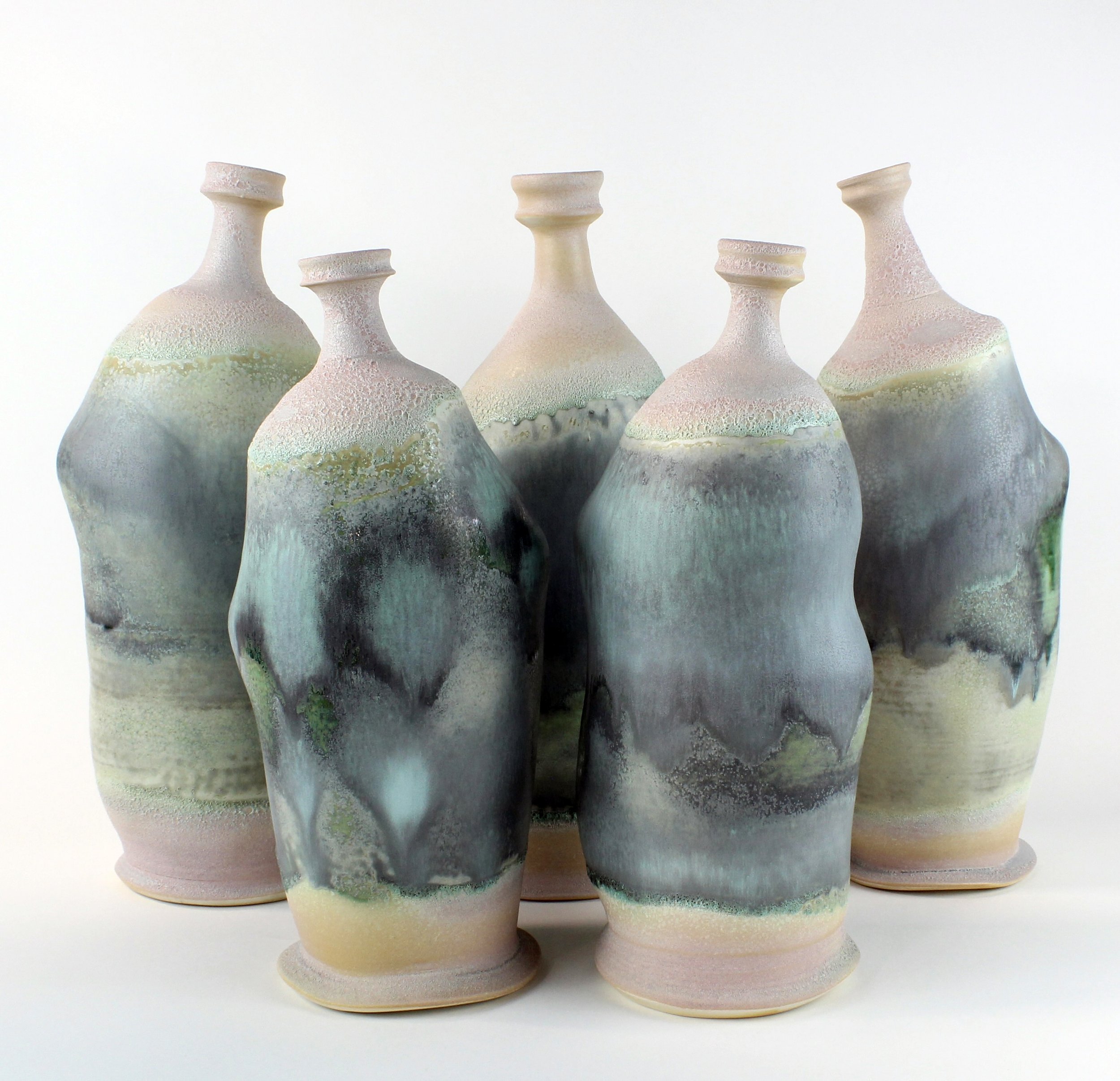 A collection of handcrafted ceramic vases with a pastel-colored, textured glaze finish, arranged in a group against a plain background.