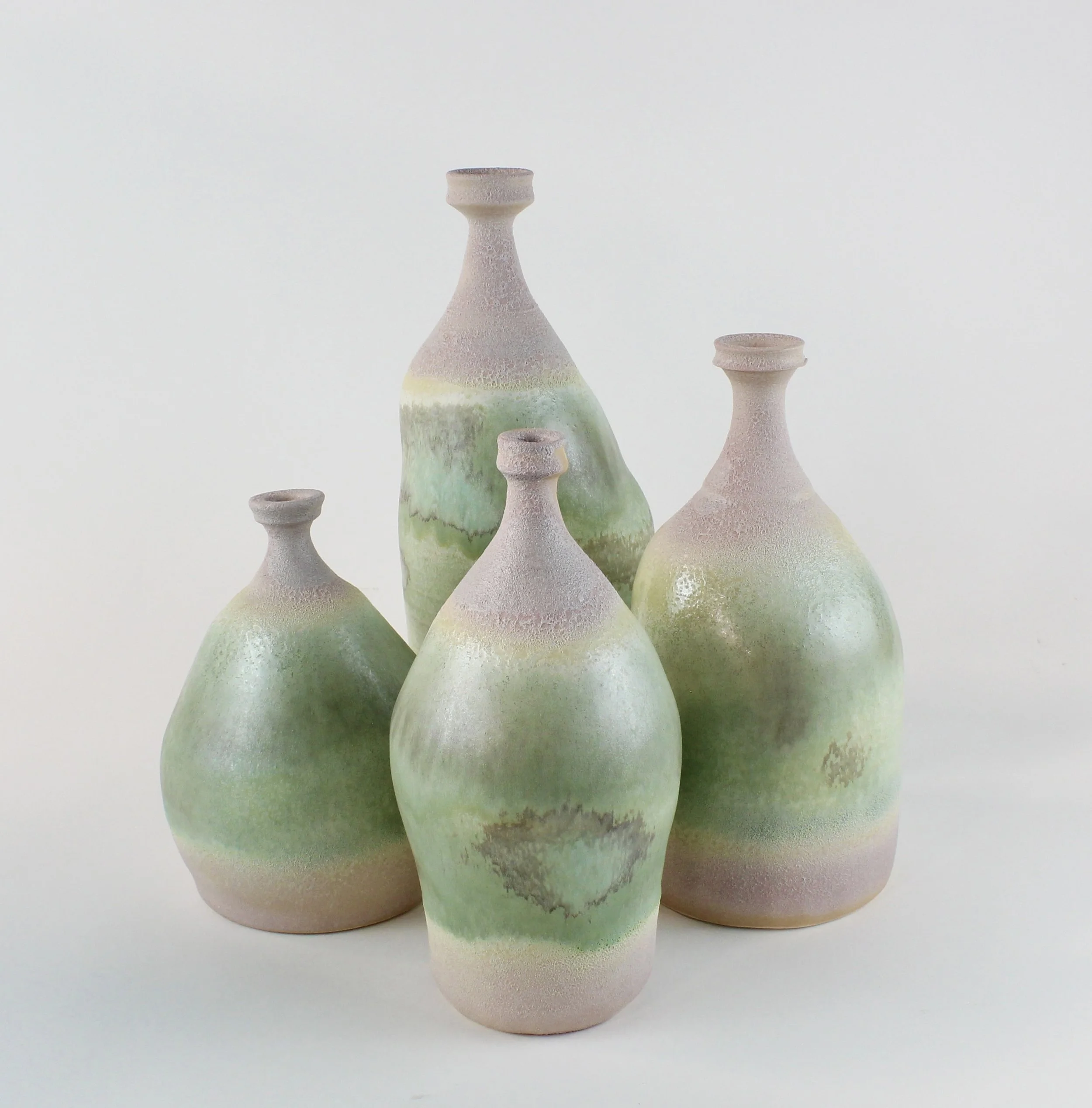 Five ceramic vases with pastel rainbow glaze, arranged on a white background.