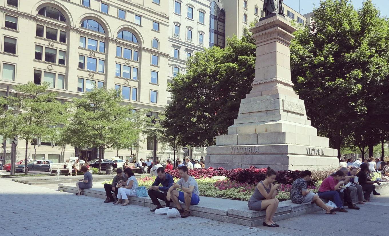 Des travailleurs sont assis et pique-niquent sur le muret entourant le Monument à la reine Victoria (1869) de Marshall Wood, au square Victoria. © Denise Caron