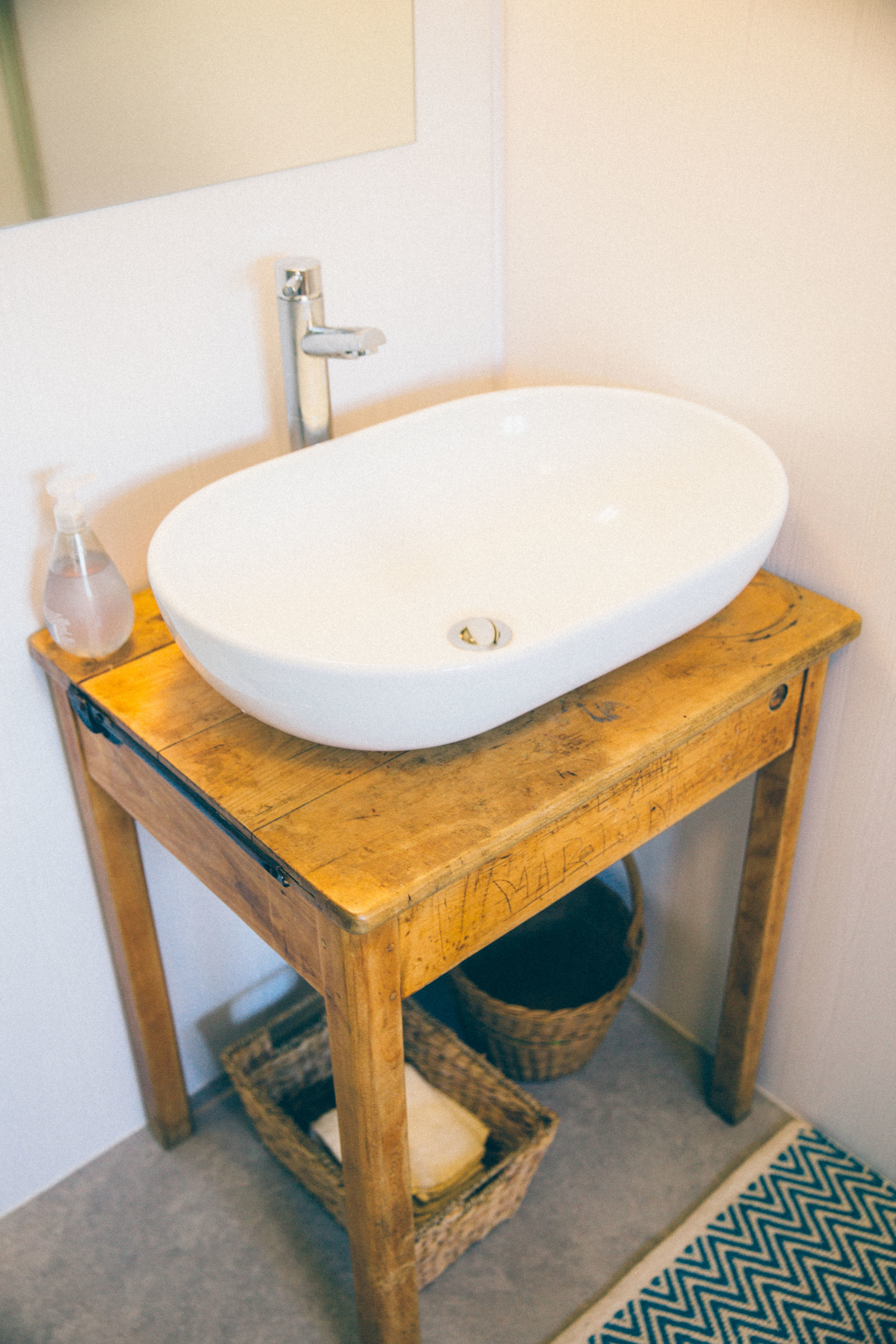 Wash bowl sink on an old school desk with baskets for flannels underneath