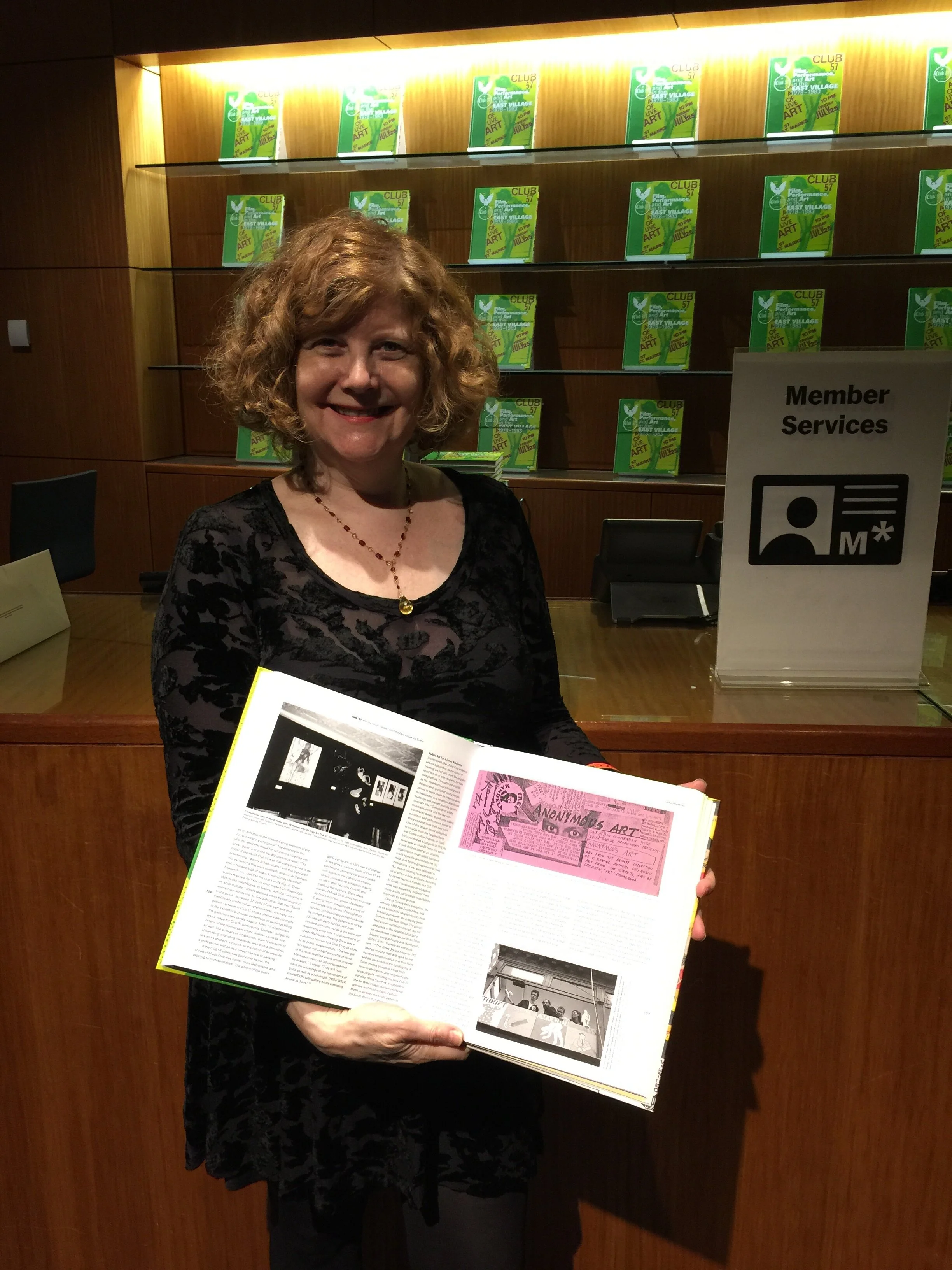 Amy Chaiklin at MoMA holding Club 57 Exhibition Cataloug