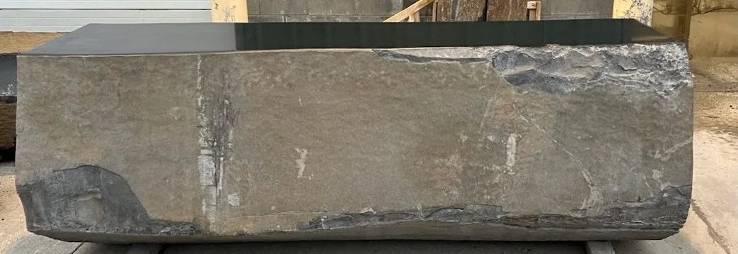 Large rectangular stone block with rough surface, gray coloration, and some natural imperfections.