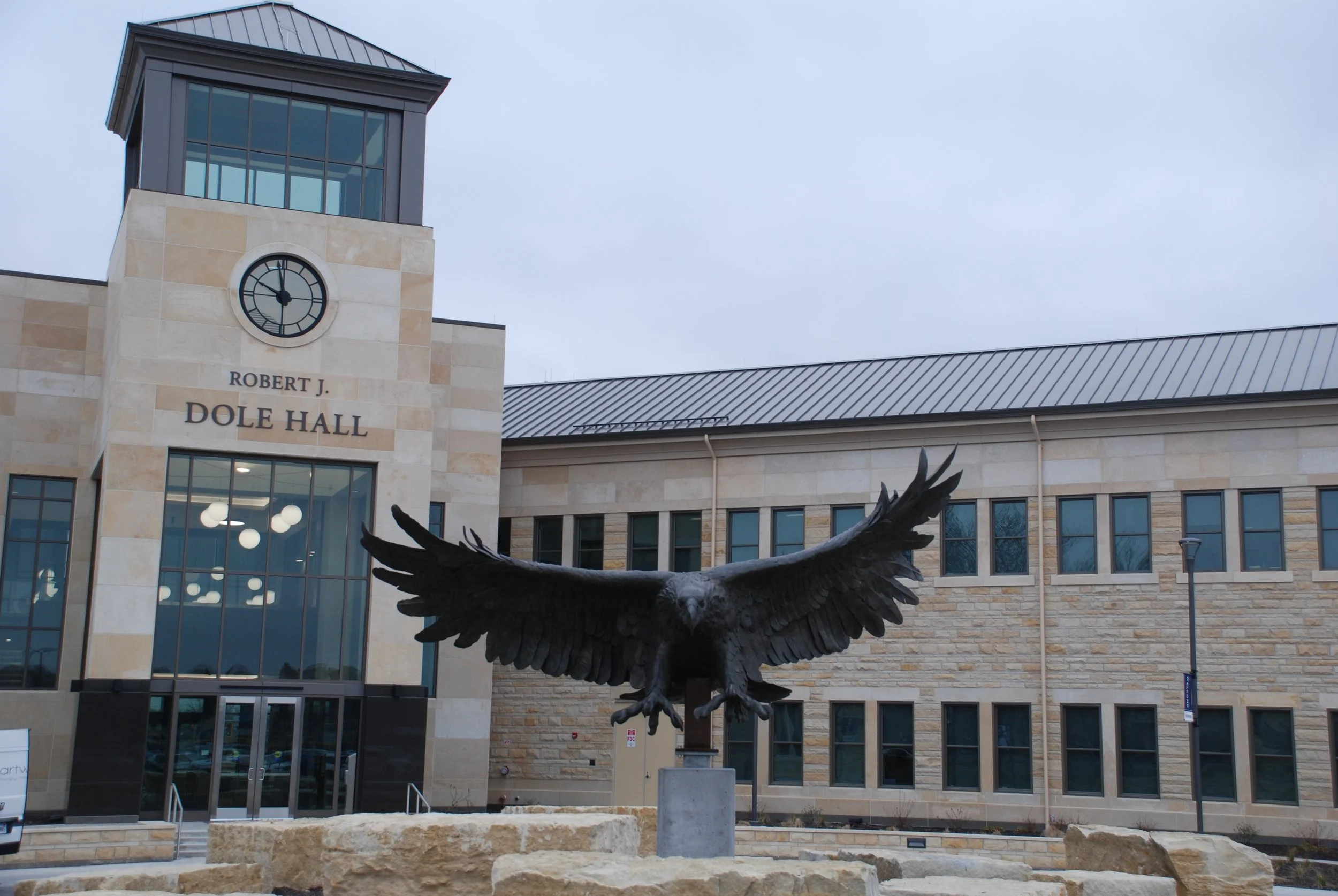Photo of Robert J. Dole Hall with a statue of an eagle with outstretched wings in front of it.