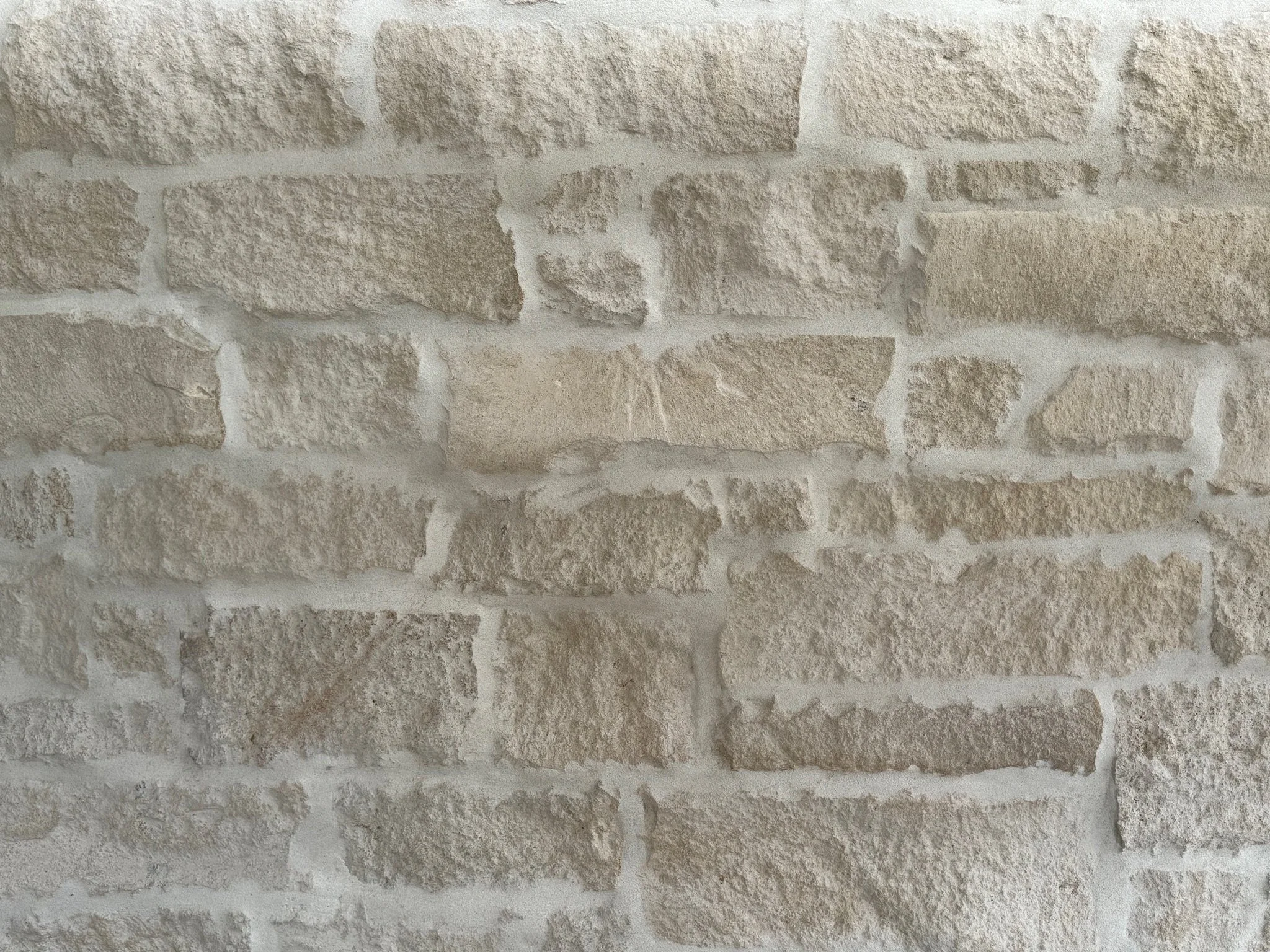A close-up view of a beige brick wall with light-colored mortar.