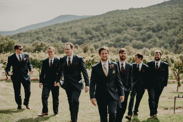Groomsmen walk through vineyards