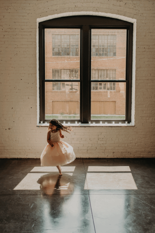 Flower girl spins in the window light of the wedding venue in Chicago, Illinois