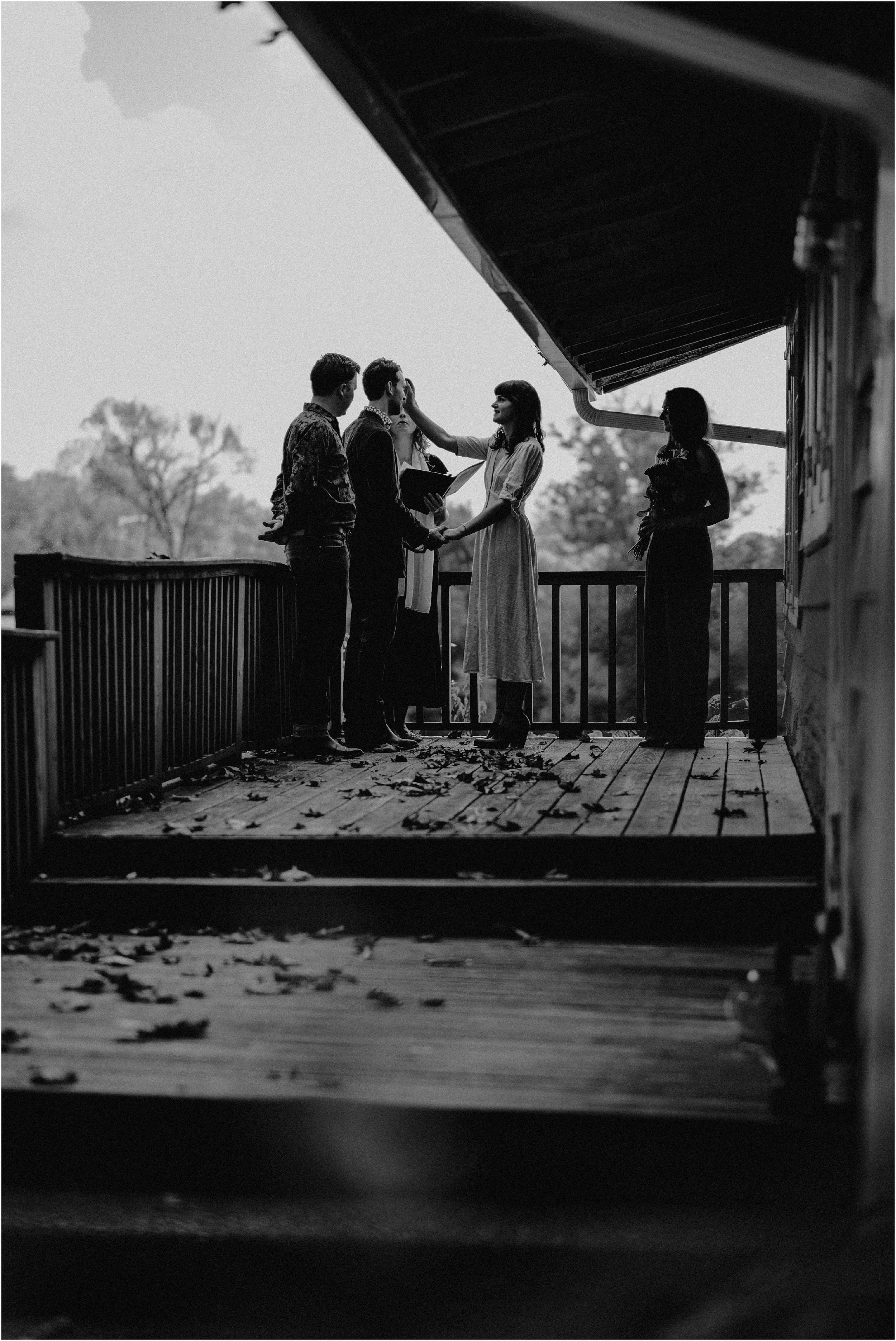 The bride sweeps the groom’s hair from his forehead during their vow ceremony