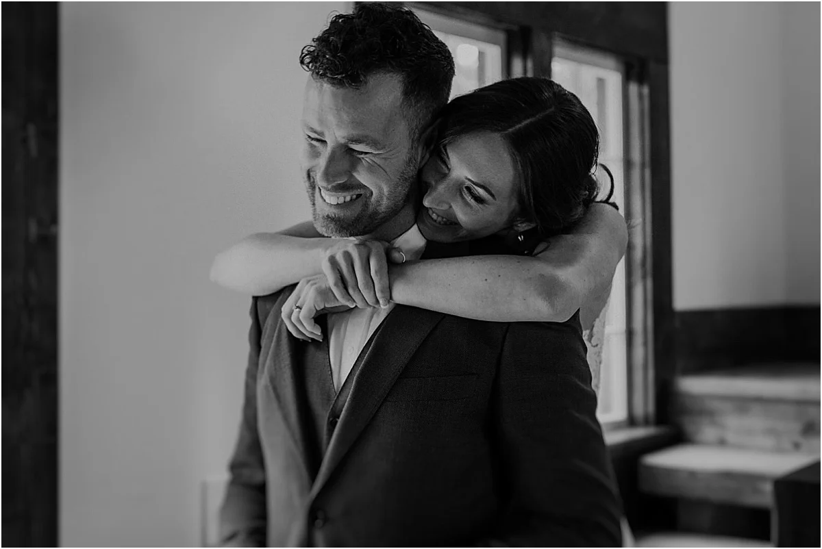 bride embracing smiling groom in black & white