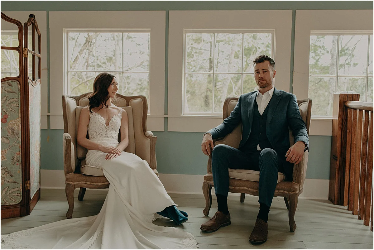 bride and groom sitting in antique chairs in blue room