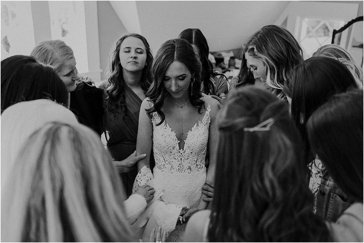 bridesmaids praying over bride before her wedding ceremony
