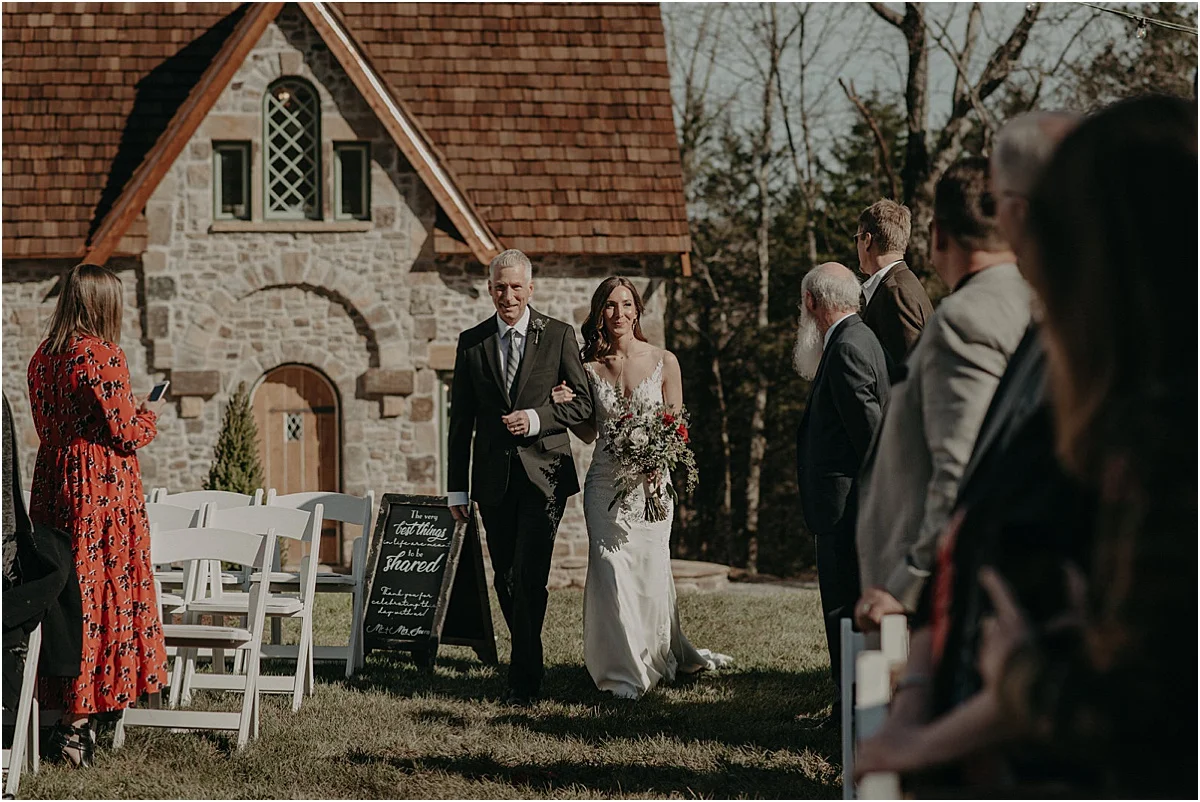 father of the bride walking bride down the aisle at outdoor wedding