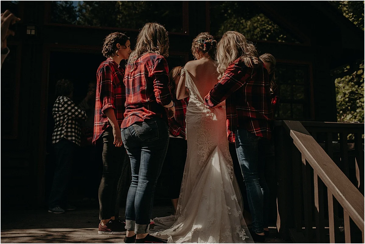 bridesmaids helping bride button wedding dress before ceremony