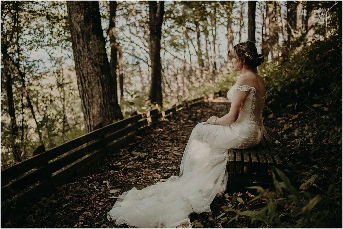 bride sitting on bench in woods before wedding ceremony