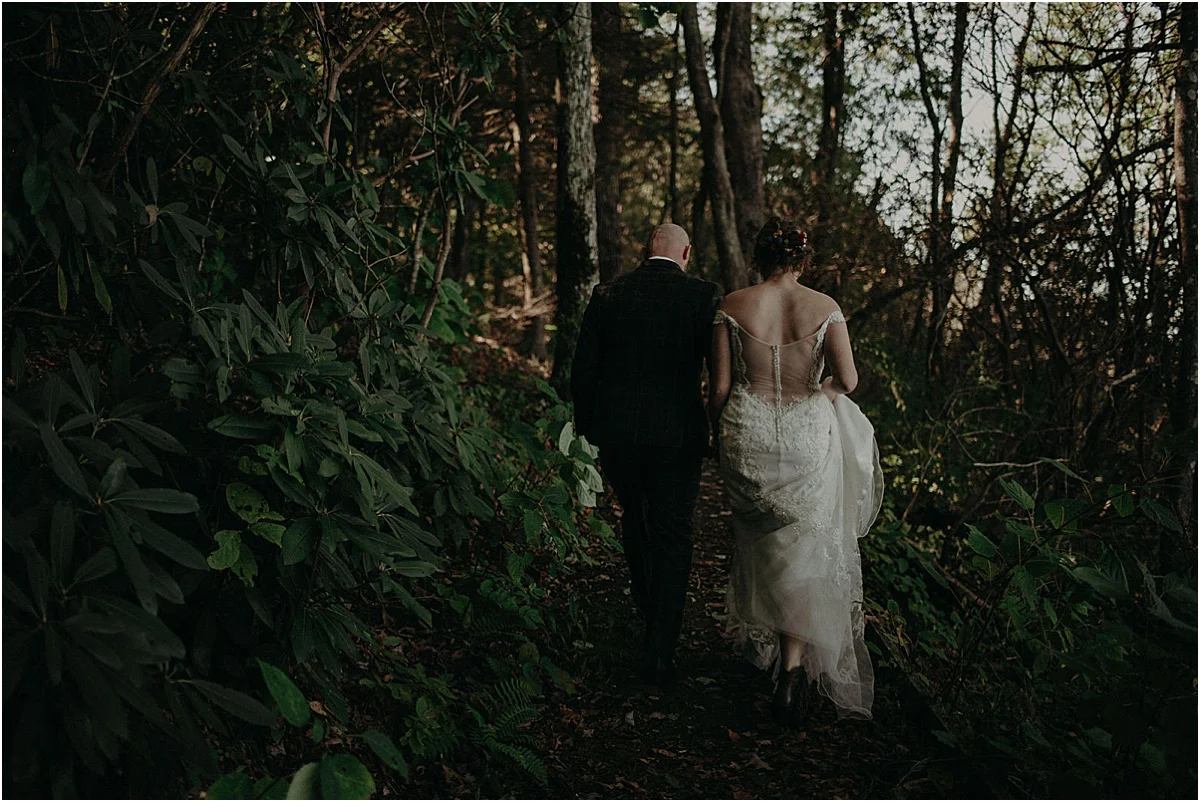 bride and groom walking through green forest in north carolina