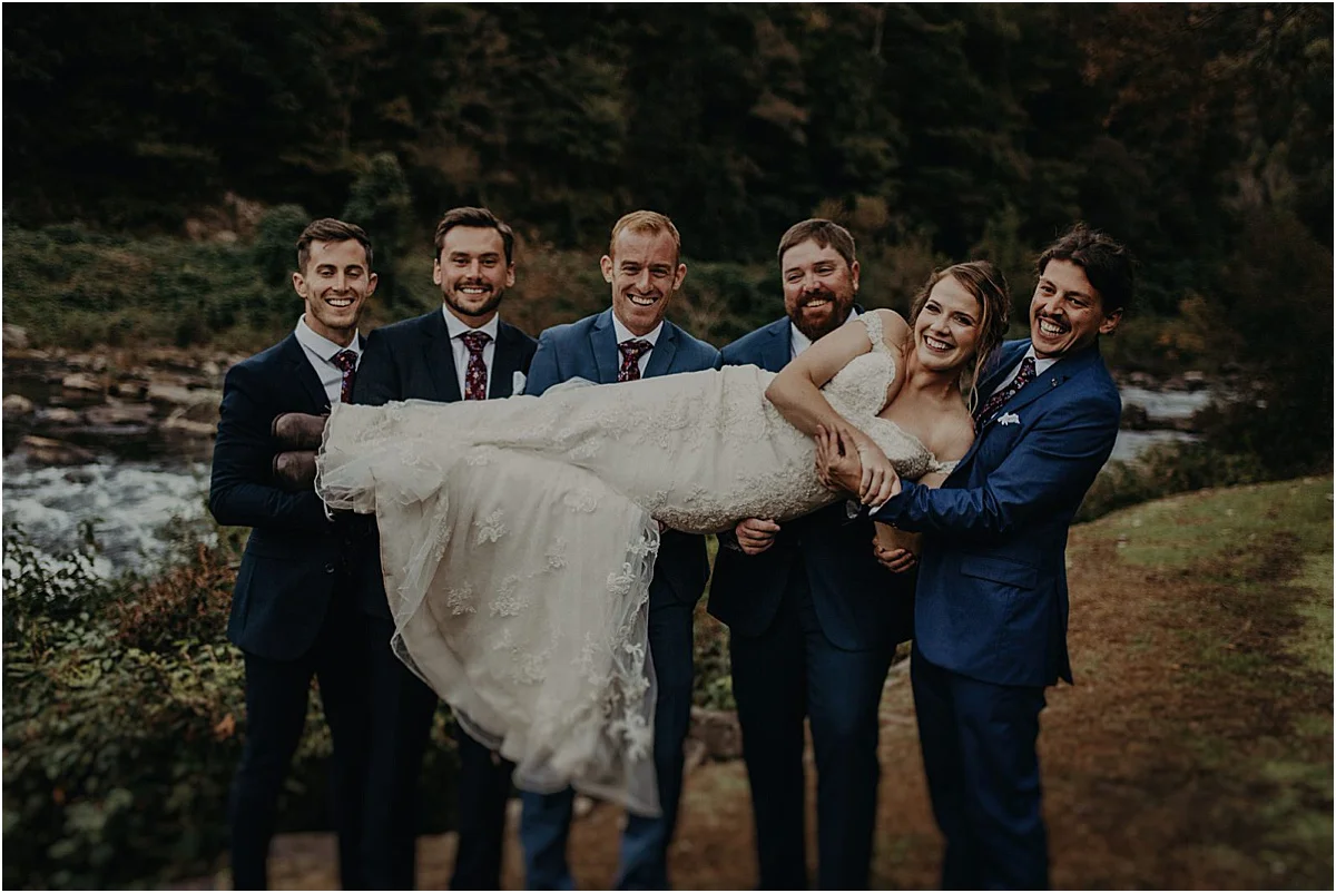 groomsmen holding up bride after ceremony