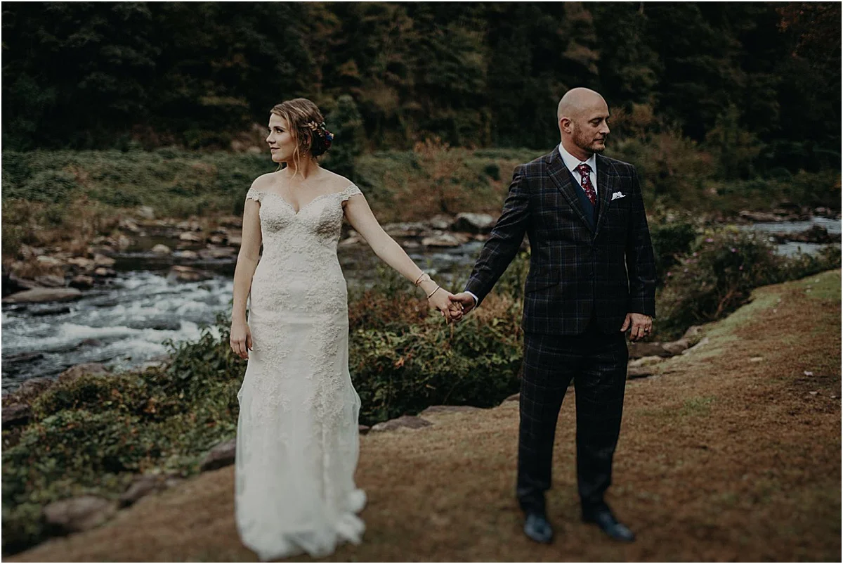 bride and groom holding hands in front of river