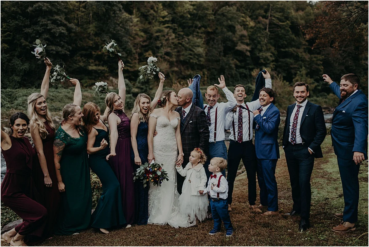 bridal party celebrating while bride and groom kiss