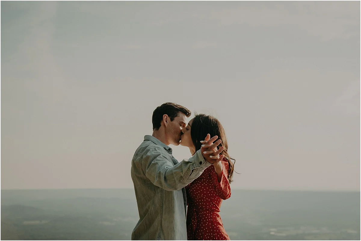couple holding hands in kissing over tennessee hills