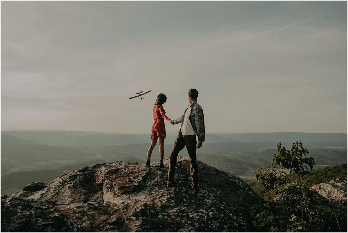 plane flying over couple holding hands in tennessee hills