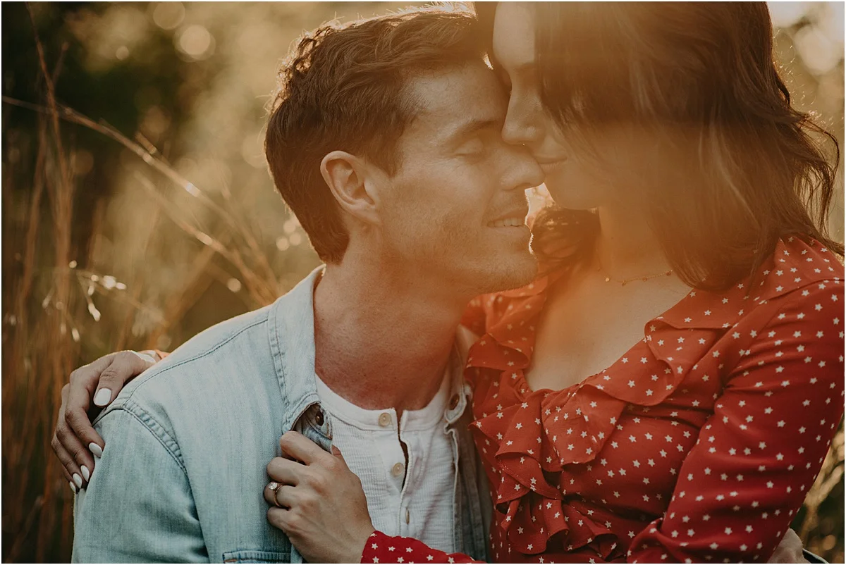 engaged couple embracing in the woods and sunlight