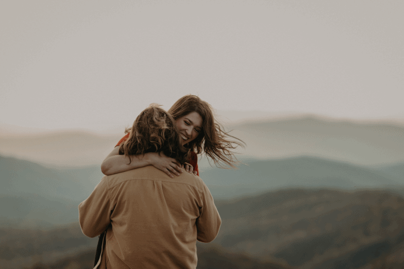 The groom twirls around the bride at this beautiful mountaintop engagement session