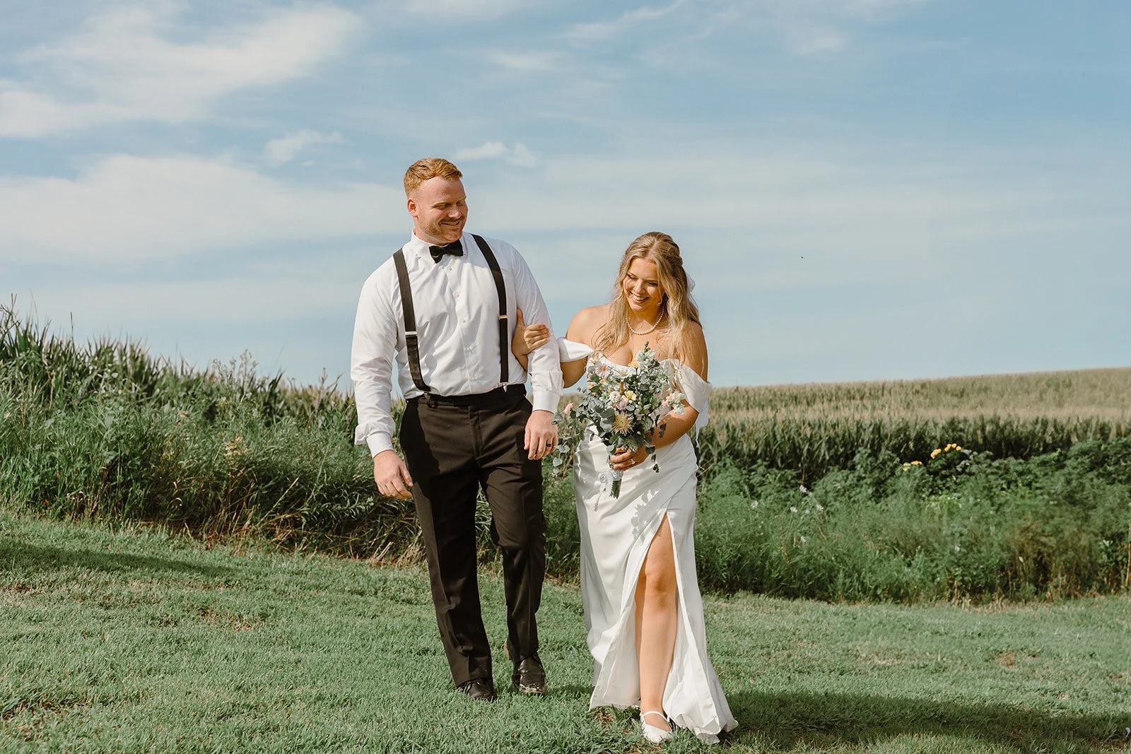 bride and groom outdoors walking on their home farm near rochester mn