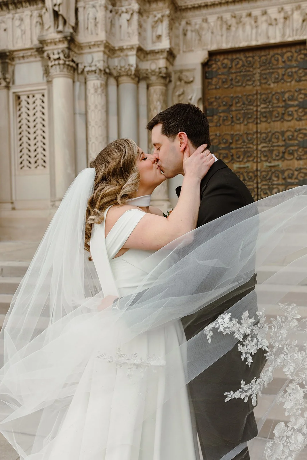 bride and groom kissing outside St. Thomas More Catholic church in st. paul