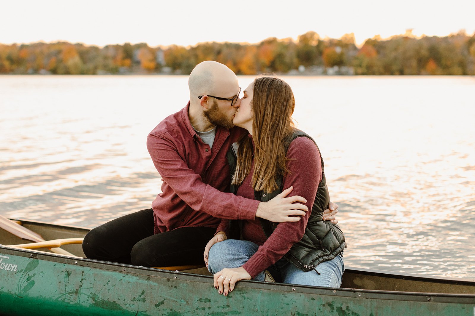 engaged couple kissing in a canoe on the lake at sunset