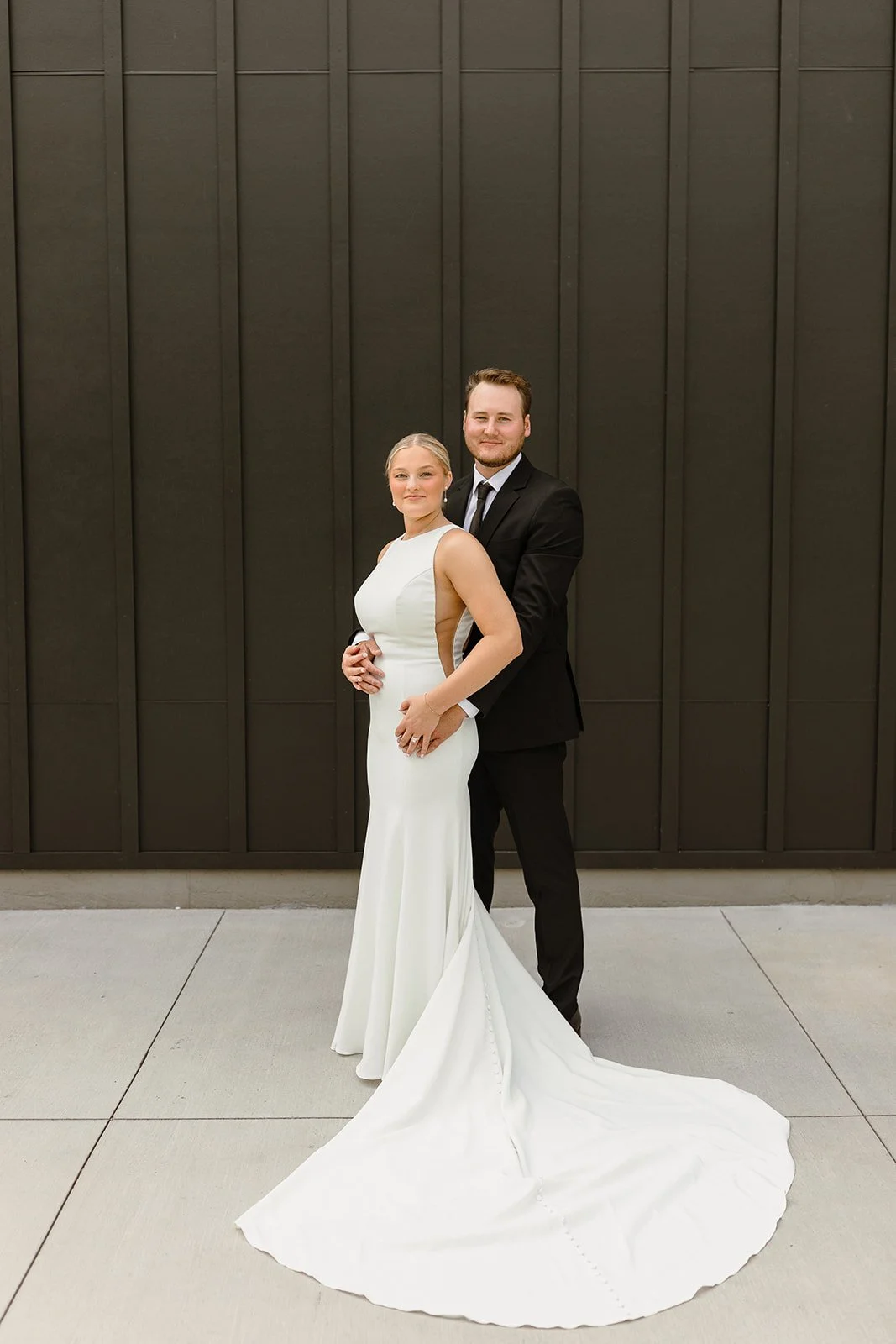groom holding bride outside white & sable on wedding day