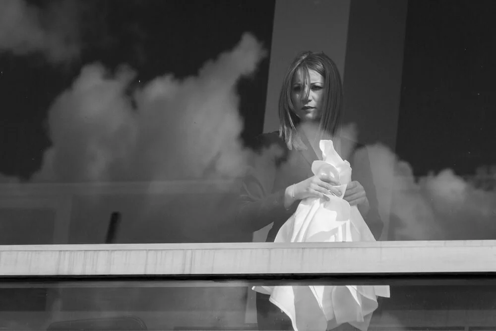 A candid photograph of a young lady with the reflections of the clouds, taken at South Bank in London