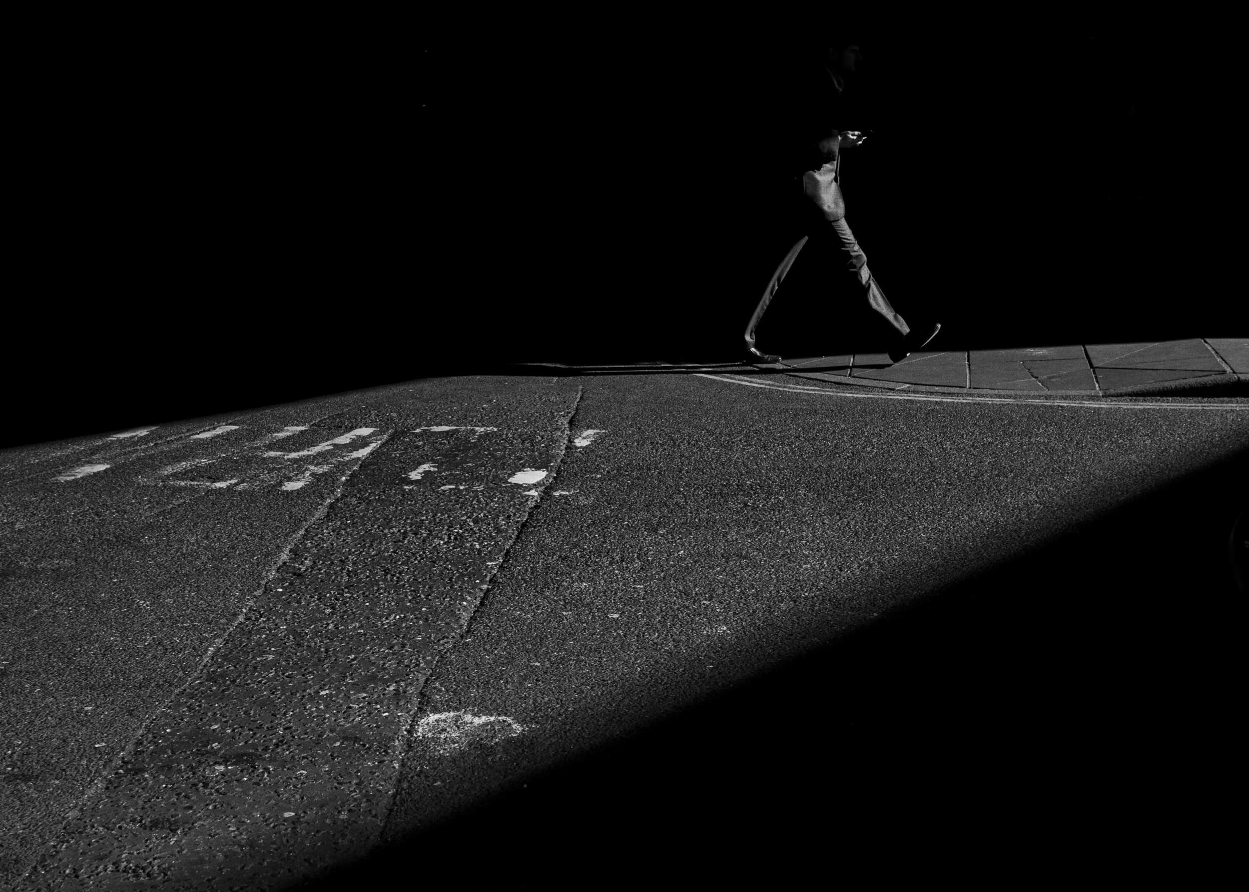 A high contrast photograph of a man walking taken using LUMIX GX7 near London Borough Market.