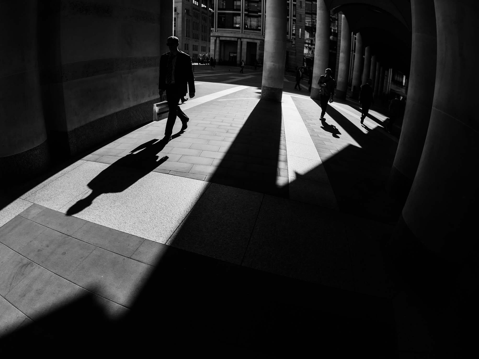 A high contrast photograph with shadows of people taken near London Stock Exchange using a Fisheye lens