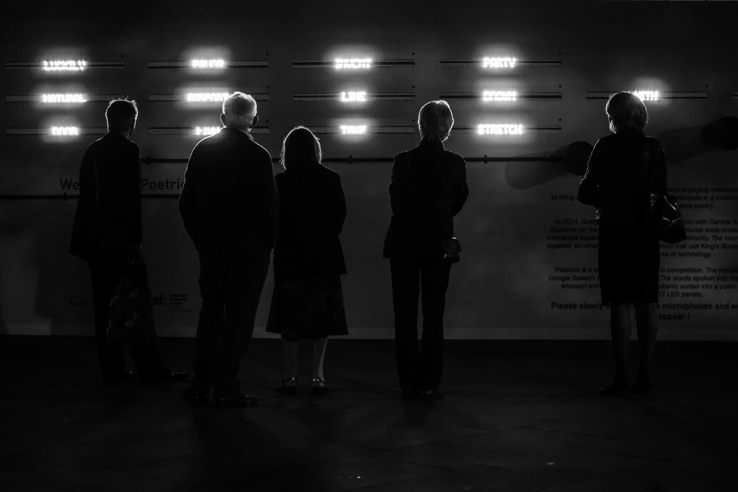 A photograph of a group of people interacting with the Poetrics installation outside King's Cross Station in London