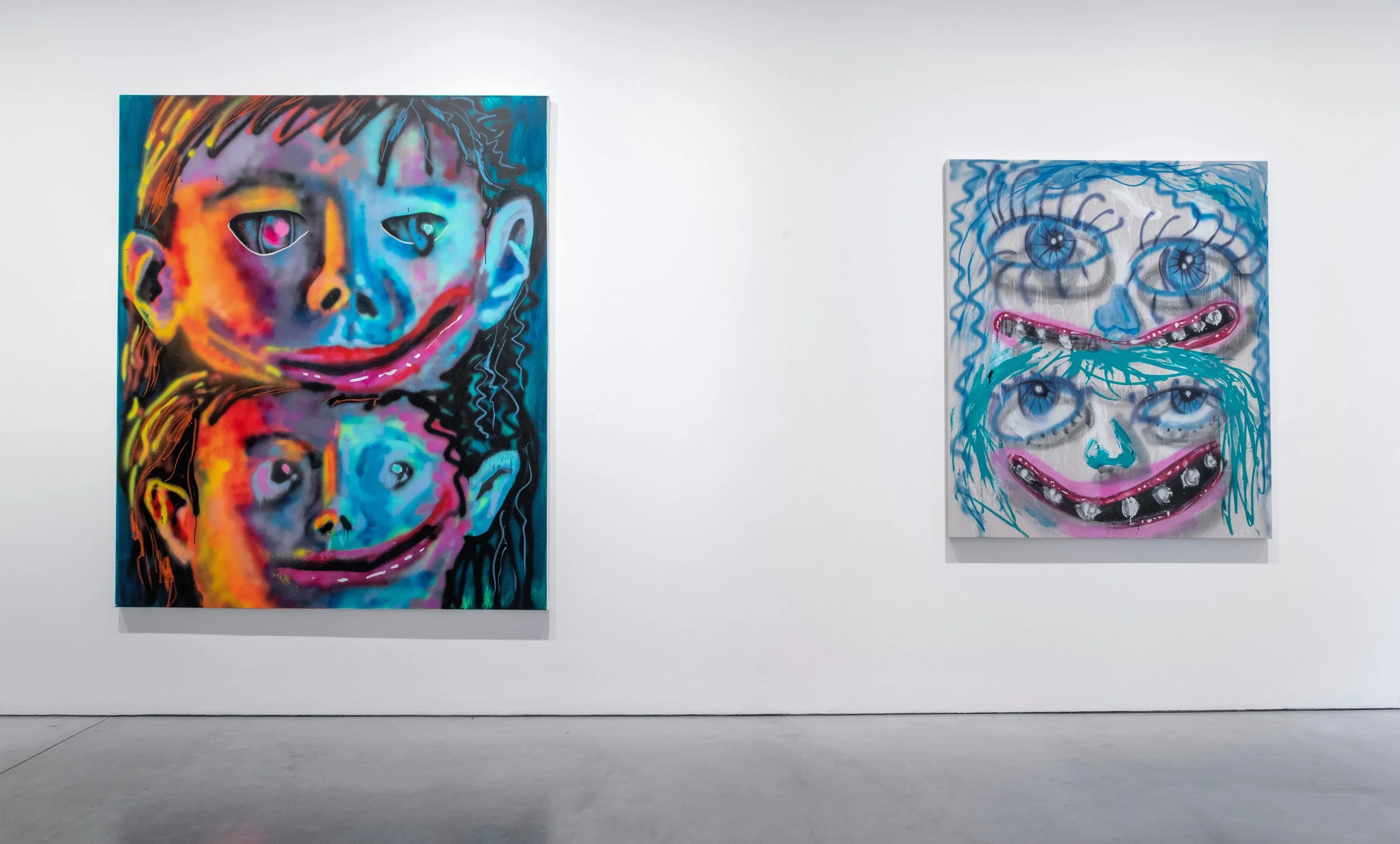  two paintings of stacked faces by Natalie Westbrook in a gallery 
