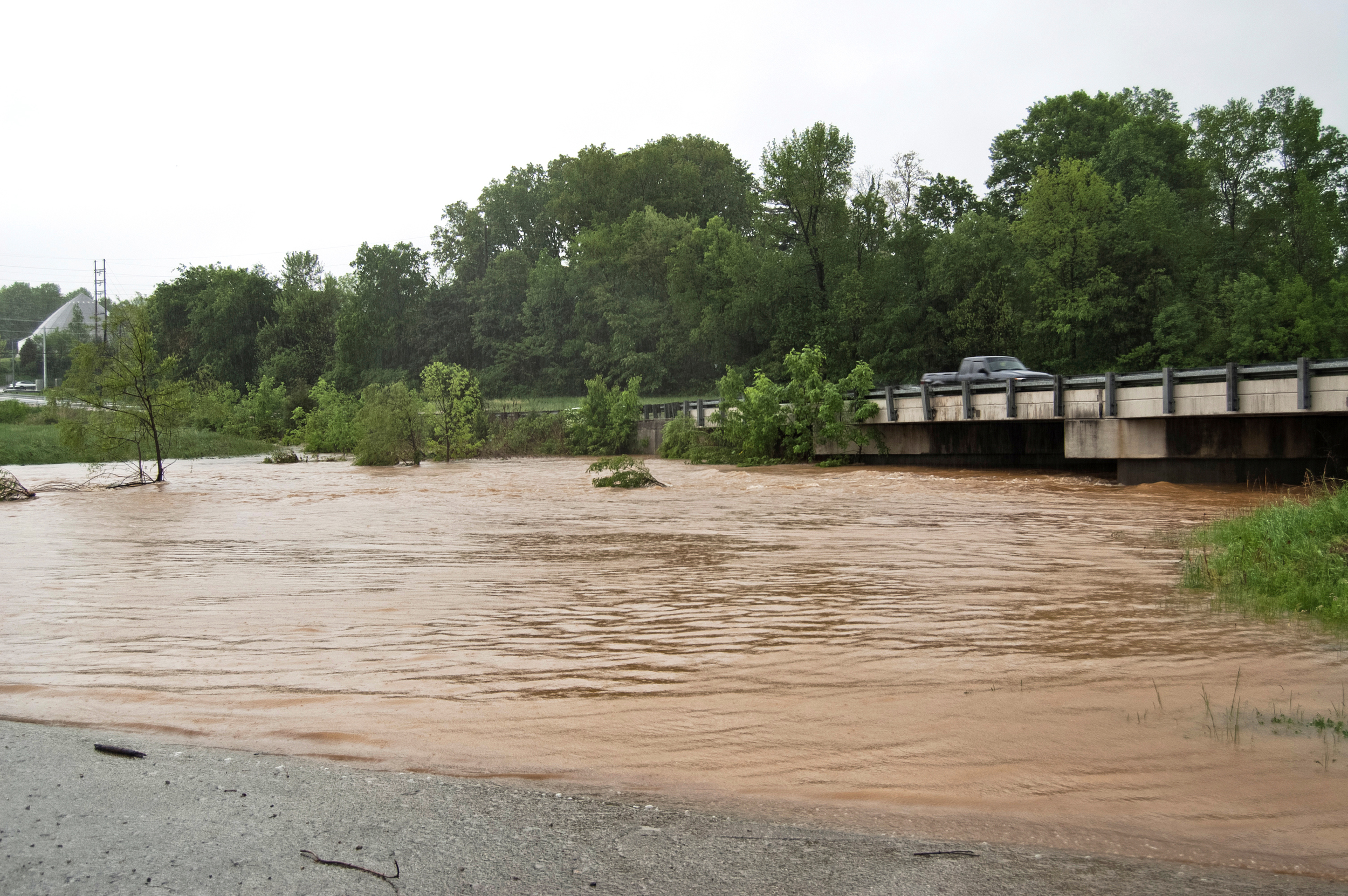 High water rapidly flows under the bridge on Trojan Trail.