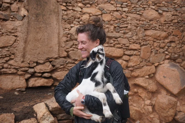 Kate and a goat having a moment of endearment after having tea with a family in a village.