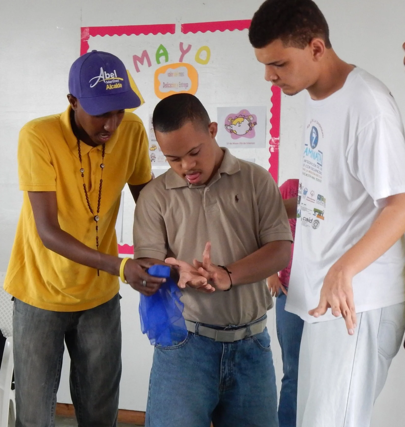 Cesar and Estarlin help their classmate with a game that develops their motor skills.