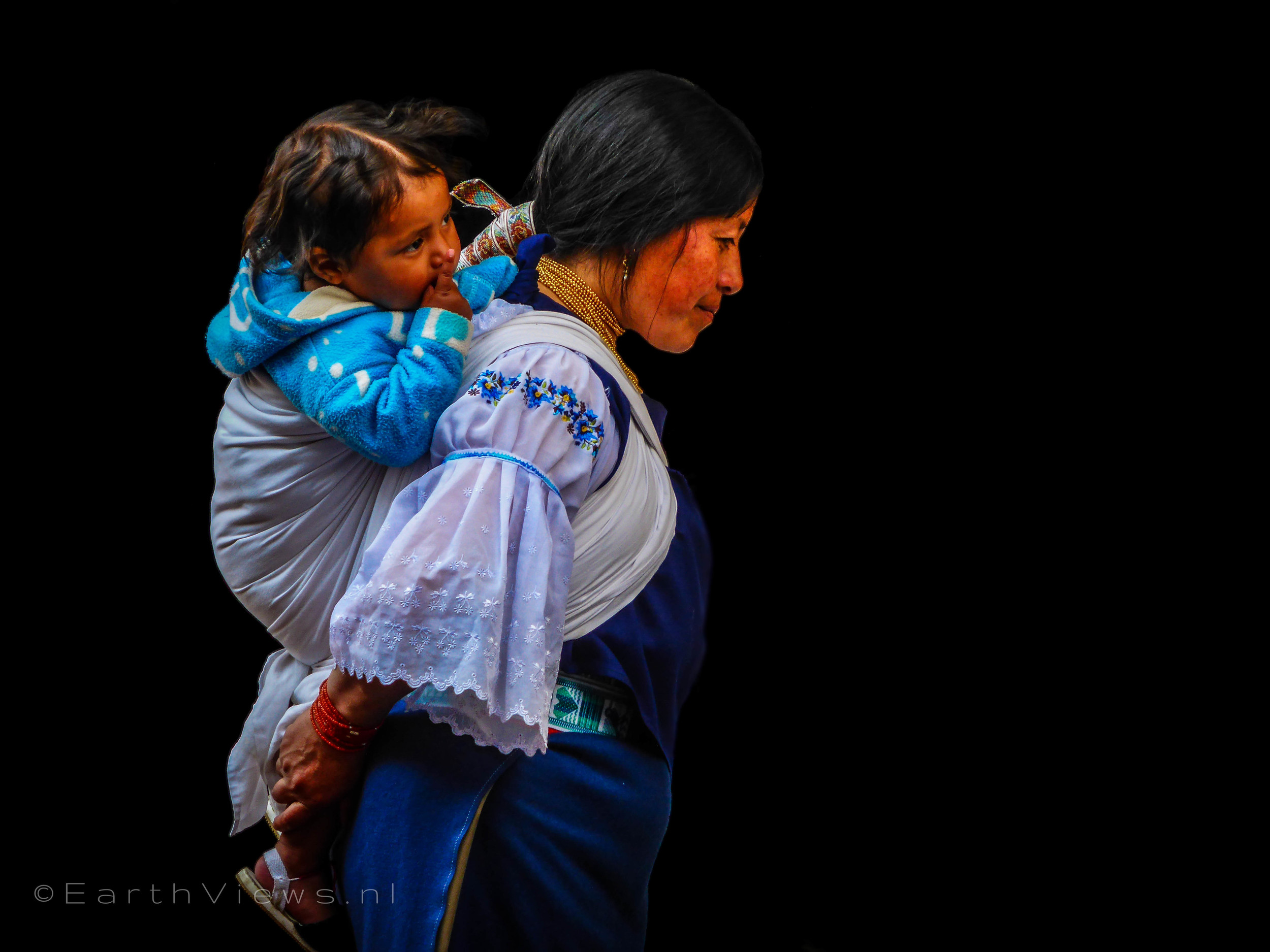 An Otavaleña in traditional style with her child on the Otavalo market.