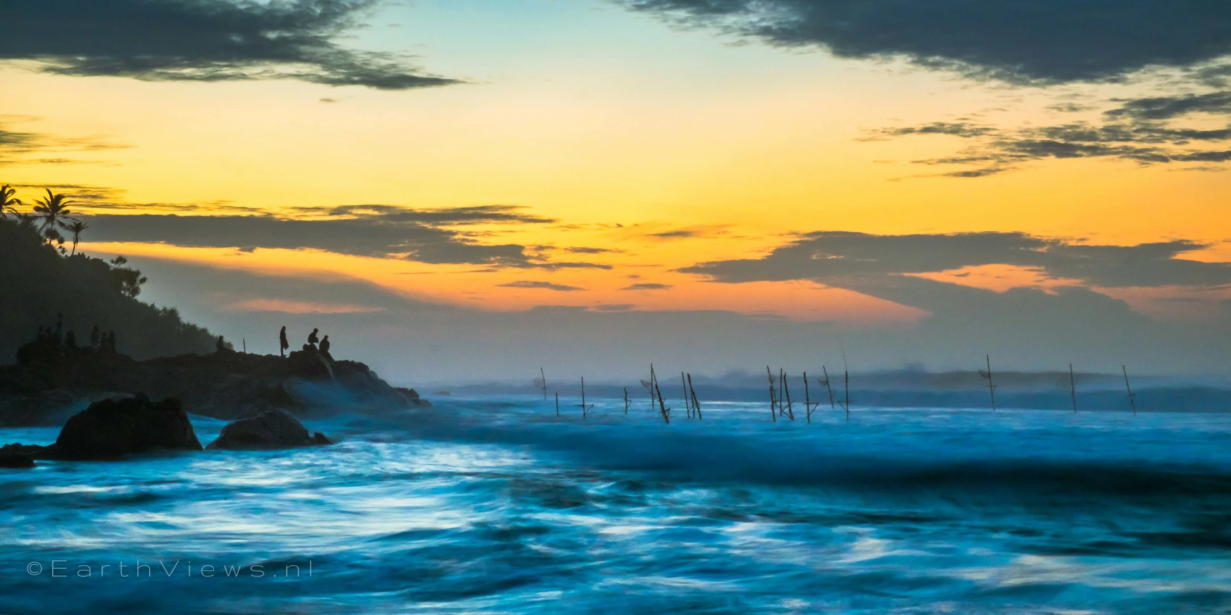 People (fishermen?) observing the rough ocean during morning twilight at the beach in Weligama, Sri Lanka.