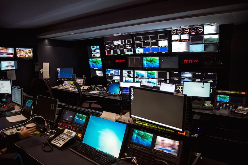 TV Broadcast news studio with many computer screens and control panels for live air broadcast.