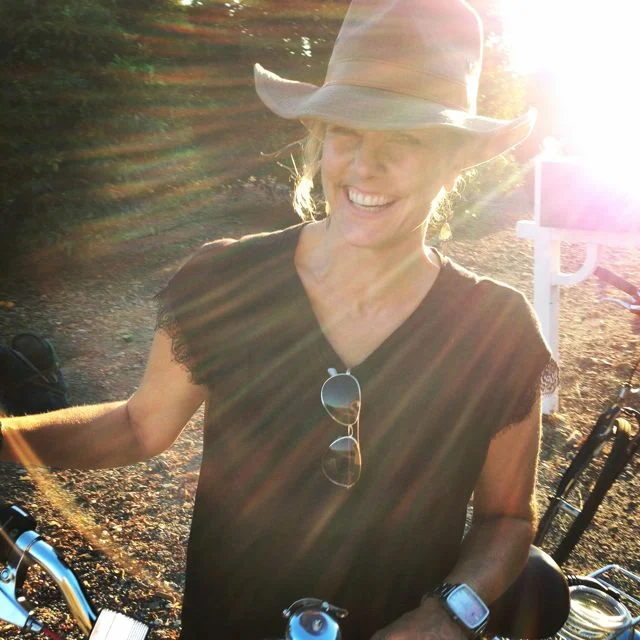 Founder, Michele Melonas, riding her bike through orange groves in Ojai.