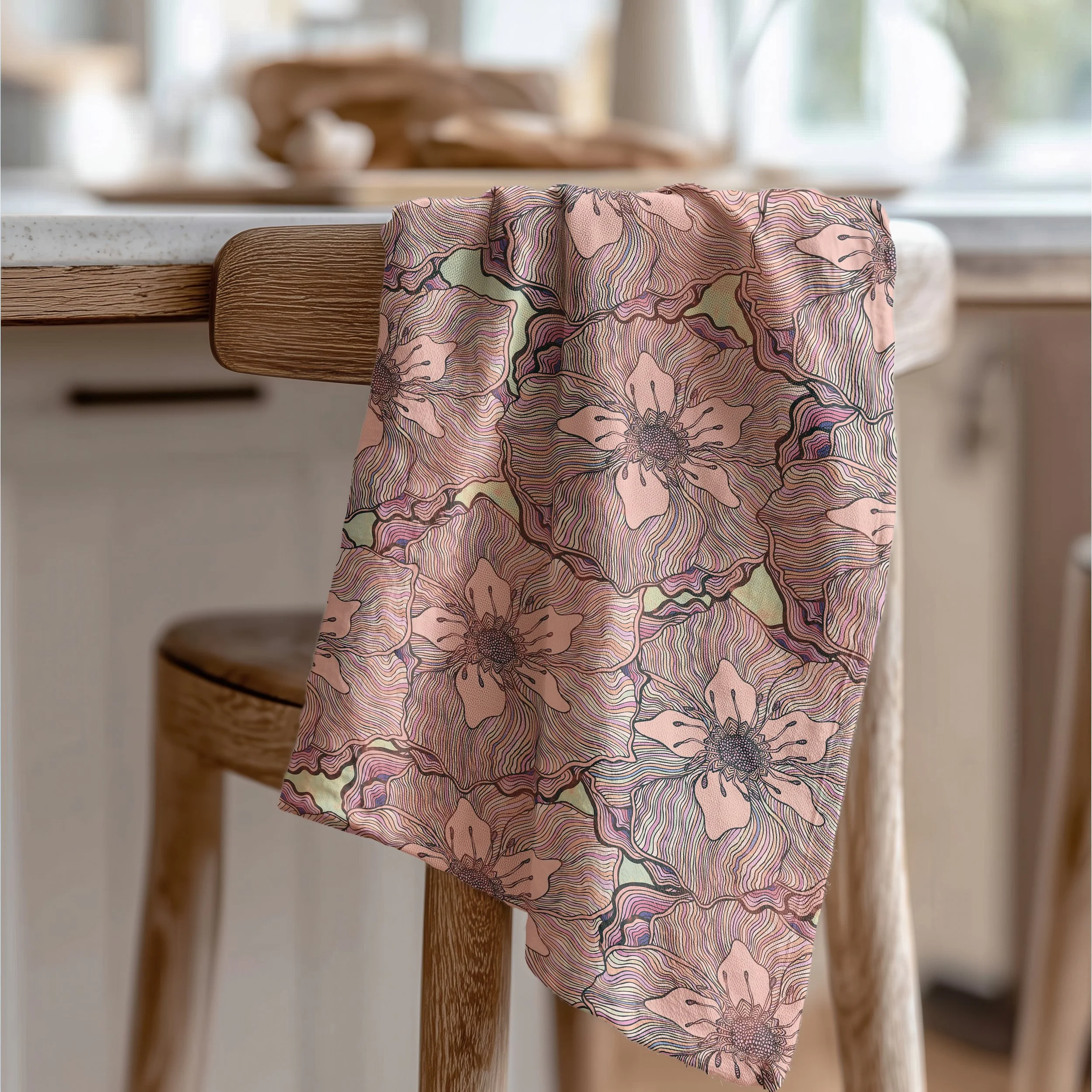 A floral patterned cloth with pink, purple, and green colors hanging over a wooden chair.