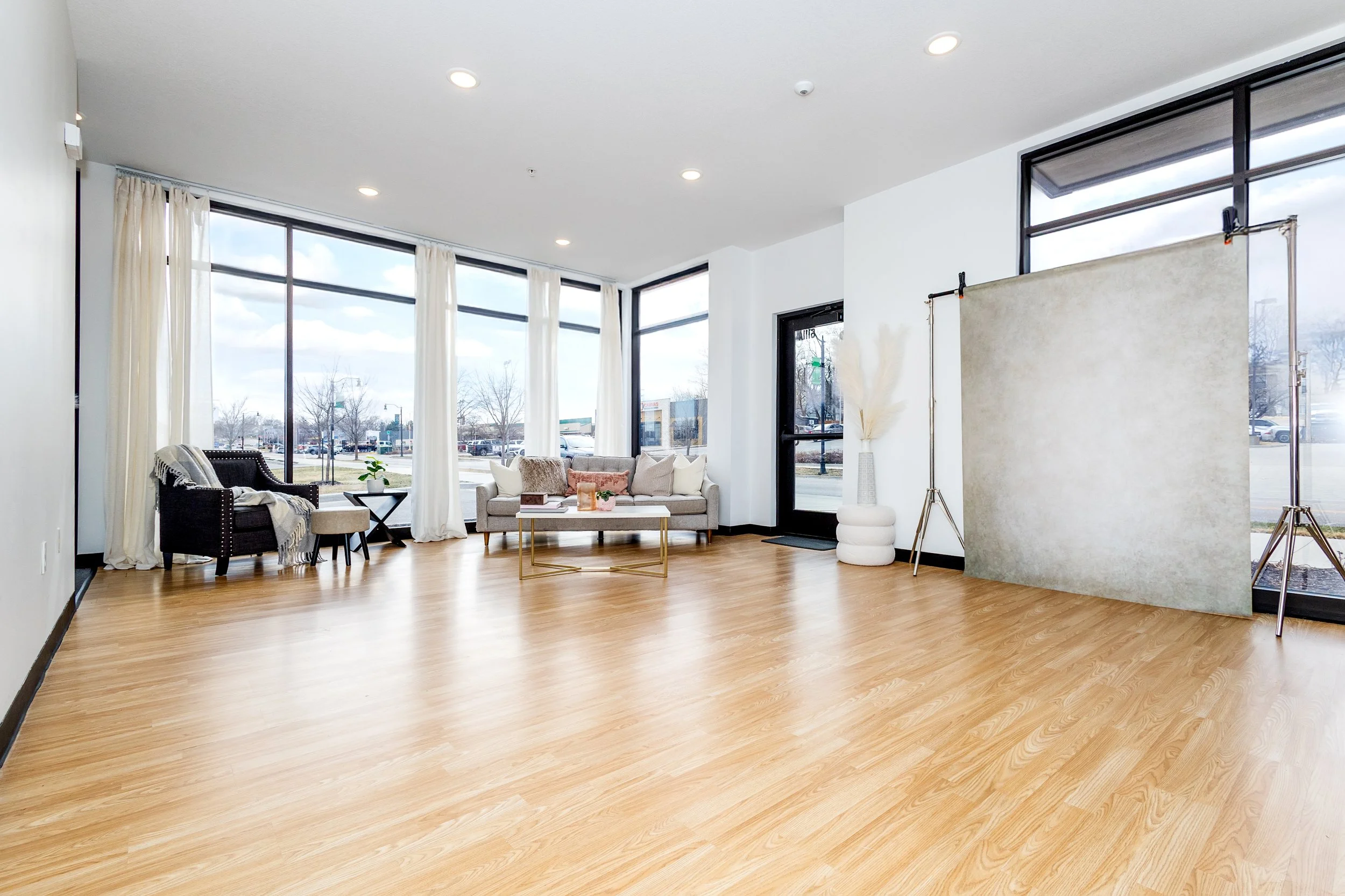 Image is a portrait studio with lots of windows for natural light and a neutral aesthetic