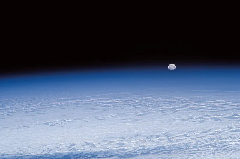 Moon rising through Earth's blue atmosphere